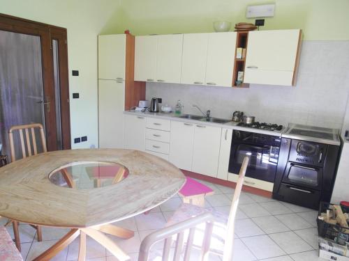 a kitchen with a wooden table with chairs and a stove at Gästezimmer Casa Lundo 52 in Comano