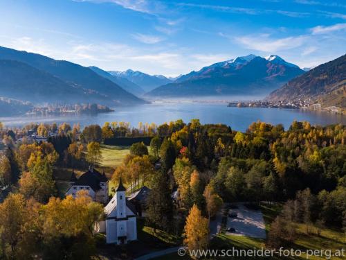 an aerial view of a lake and a church at Schloss Prielau Hotel & Restaurants in Zell am See