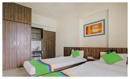 a hotel room with two beds with green pillows at Welcome Service Apartments in Mumbai