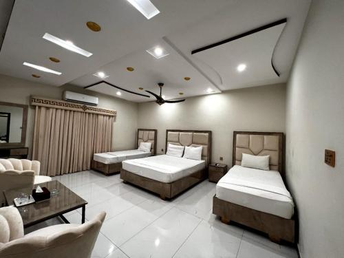 una camera con due letti e un soggiorno di Dove Inn Hotel a Lahore