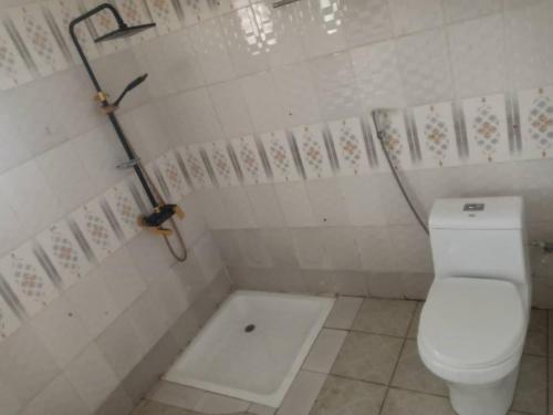 La salle de bains est pourvue d'une douche et de toilettes blanches. dans l'établissement Costal Road hideout, à Brufut