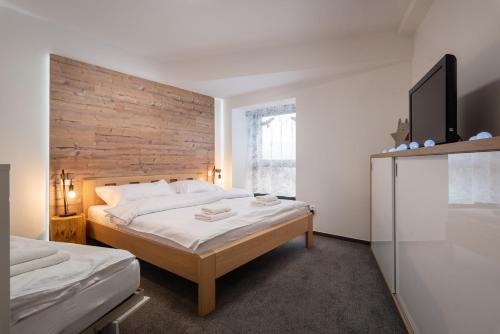 a bedroom with two beds and a wooden wall at TATRYSTAY Armeria Apartments in Vysoke Tatry - Strbske Pleso