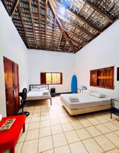 Habitación con 2 camas y mesa roja. en Cacerola Beach House en Poneloya