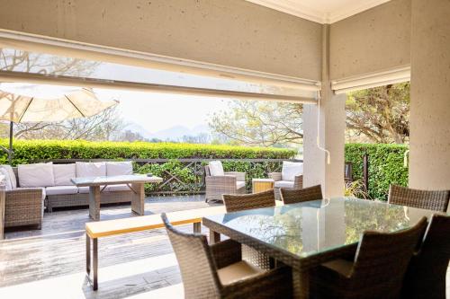an outdoor patio with a glass table and chairs at Modern Large 5 bedroom Villa in Pecanwood Golf Estate in Hartbeespoort