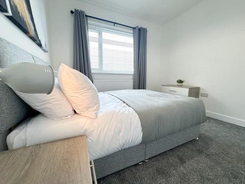 a bedroom with a bed with white sheets and a window at High Market Place by Blue Skies Stays in Ashington