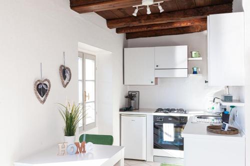 a white kitchen with white cabinets and a table at -Ortaflats- Appartamento l'Isola in Orta San Giulio