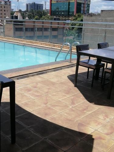 a table and chairs on a roof with a pool at Joy suites emeli in Nairobi