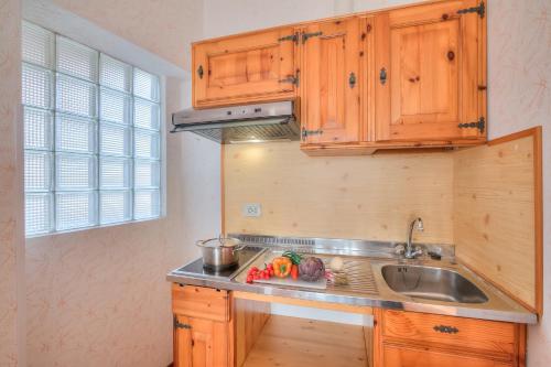 a kitchen with wooden cabinets and a sink at Residence Bellevue Country Style - Happy Rentals in Tremosine Sul Garda