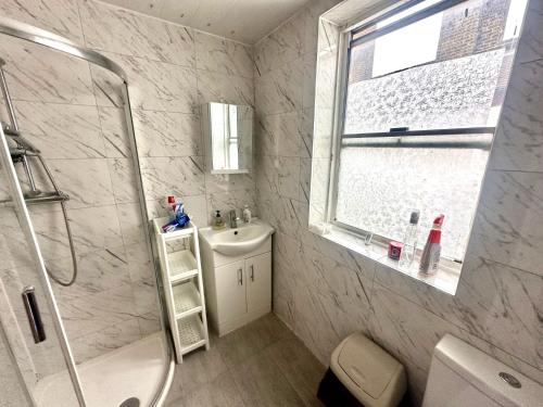 baño blanco con ducha y lavamanos en Bethnal Green Rooms R3 en Londres