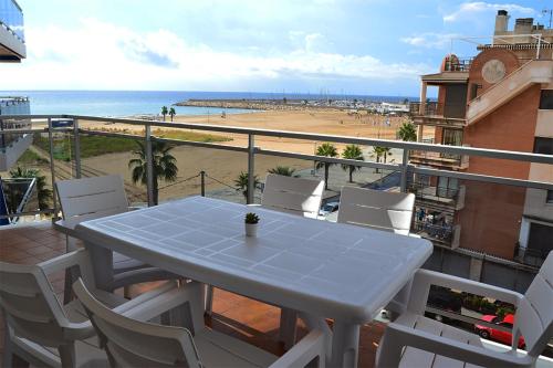 einen Tisch und Stühle auf einem Balkon mit Strand in der Unterkunft Luz Marina in Torredembarra