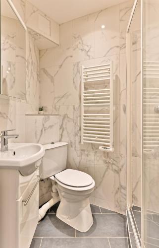 une salle de bain blanche avec des toilettes et un lavabo dans l'établissement Appartement au cœur du Marais - IV, à Paris