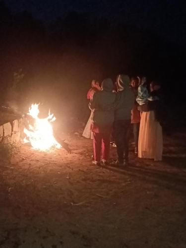 a group of people standing around a fire at night at SD Residency - Yercaud in Yercaud