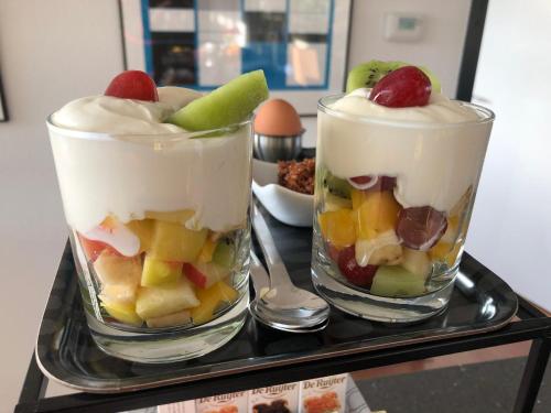 two glasses filled with fruit and whipped cream on a tray at BEDbijPET in Emmen
