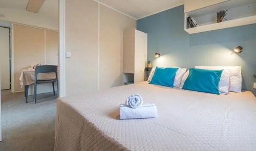 een slaapkamer met een groot wit bed met blauwe en witte kussens bij Mobil Home les pieds dans l'eau in Sarzeau