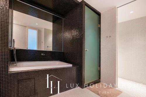 a bathroom with a bath tub and a mirror at LUX The Elegant DIFC Suite in Dubai