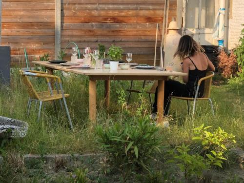 a woman sitting at a table in a garden at Peaceful House & Garden (20min EU & City Center) in Brussels