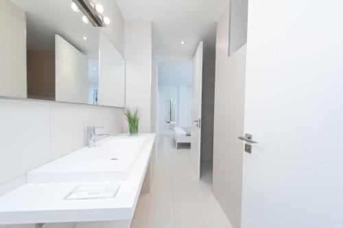 a white bathroom with two sinks and a mirror at Tarida in Alcudia