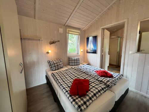 um quarto com uma cama com duas almofadas vermelhas em Ferienhaus Freibeuterweg 13 - b51130 em Lübeck