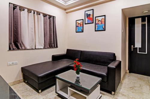 a living room with a black leather couch and a table at OYO Flagship Divya Jyoti Inn Near RDB Cinemas in Kolkata