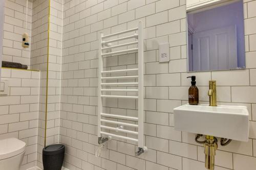 Baño de azulejos blancos con lavabo y espejo en The Lookout - Stylish penthouse with sea views en Kent