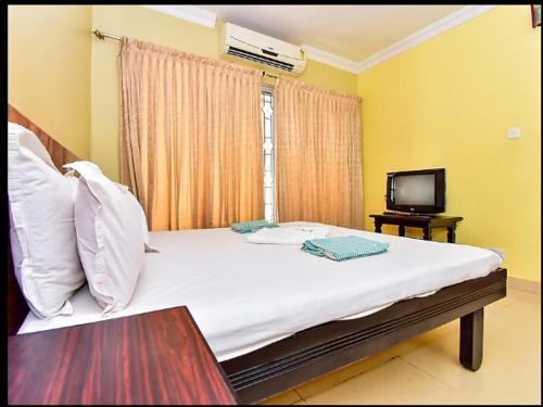 Un dormitorio con una cama con televisión y una ventana. en HOTEL SRIMANIYA, en Kanyakumari