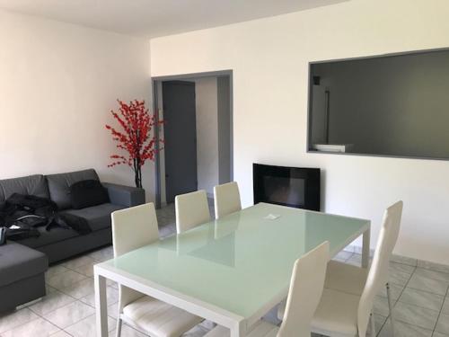 une salle à manger avec une table en verre et des chaises blanches dans l'établissement T3 pont romain Amelie les bains, à Amélie-les-Bains-Palalda