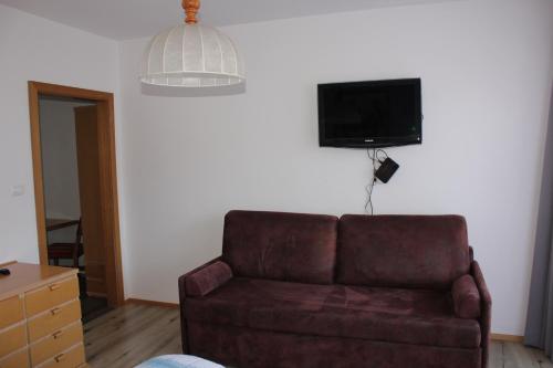 a living room with a couch and a tv on the wall at Kehrerhof in Rifiano