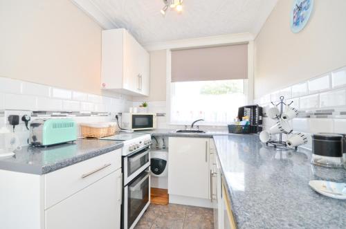 una cocina blanca con armarios y electrodomésticos blancos en 36 Sandown Bay Holiday Centre, en Brading