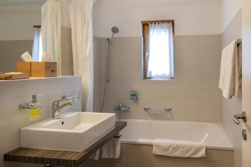 y baño blanco con lavabo y bañera. en Ferienwohnungen Hotel Allegra, en Zuoz