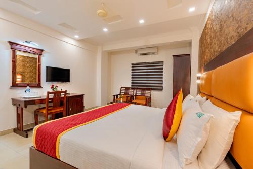 a bedroom with a large bed and a desk at Daan Orchid Residency in Kottayam