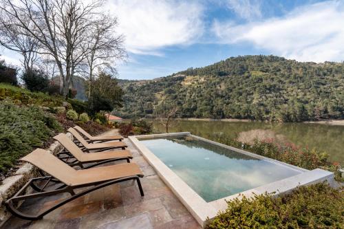 a swimming pool with lounge chairs next to a lake at VIVA Douro Countryside Lodge in Cinfães