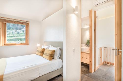 a white bedroom with a bed and a window at VIVA Douro Countryside Lodge in Cinfães