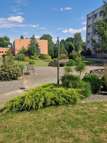 a park with benches and a pole in the grass at Kambarių nuoma Žeimelyje in Žeimelis