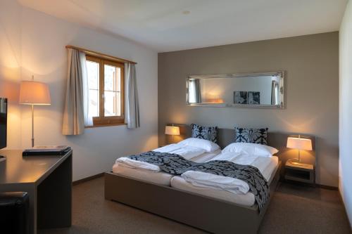 Schlafzimmer mit einem Bett und einem Wandspiegel in der Unterkunft Ferienwohnungen Hotel Allegra in Zuoz
