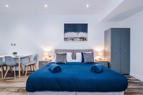 een slaapkamer met een blauw bed met een tafel en stoelen bij The Binding House in Hull