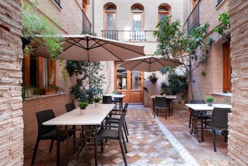 VillalongaにあるHotel Casa Babelのテーブル、椅子、パラソルのある屋外パティオ