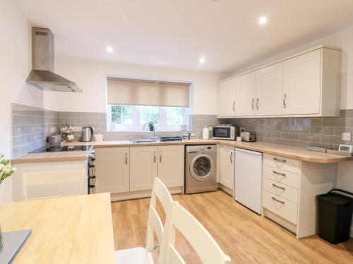 a large kitchen with white cabinets and a table at Farley Cottage II in Alton