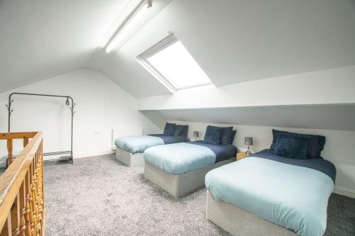 a attic bedroom with two beds and a skylight at Rochdale Train STN, Large House in Rochdale