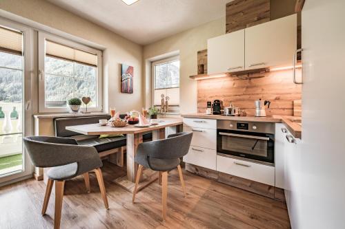 マイヤーホーフェンにあるVilla Romantica Appartementの白いキャビネット、テーブルと椅子付きのキッチンが備わります。