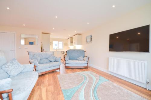 a living room with two blue chairs and a flat screen tv at Bay Reach in Sandown