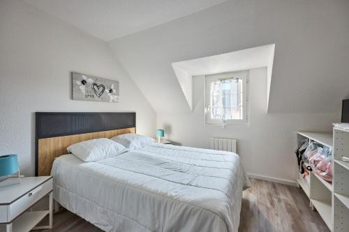 une chambre blanche avec un lit et une fenêtre dans l'établissement La Villa Fleurie - Appt à 50m de la plage, à Courseulles-sur-Mer