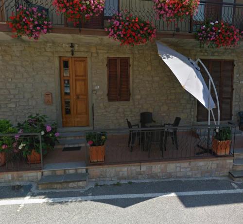 un patio con tavolo, sedie e ombrellone di Casa La Quercia a Chiusi della Verna