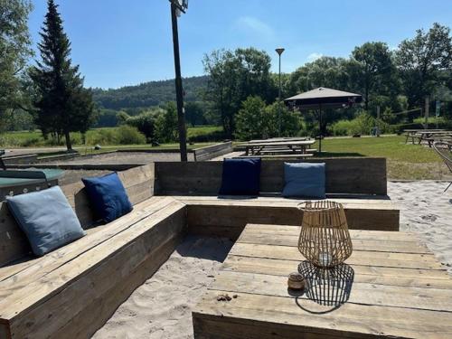 a wooden bench with blue pillows in a park at Camping De La Vallée in Durbuy