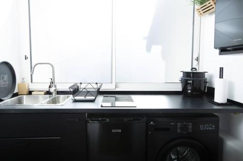 - une cuisine noire avec un évier et un lave-vaisselle dans l'établissement Studio confortable à Clermont-Ferrand, 25 m², proche centre-ville, à Clermont-Ferrand
