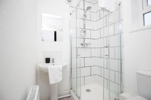 a white bathroom with a shower and a sink at HC Property - Cromwell Avenue in Newcastle upon Tyne