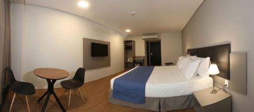 um quarto de hotel com uma cama, uma mesa e cadeiras em Fity Hotel no Recife