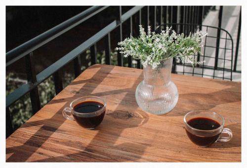 two cups of coffee on a wooden table with a vase at Arias Apartments in Nea Kalikratia