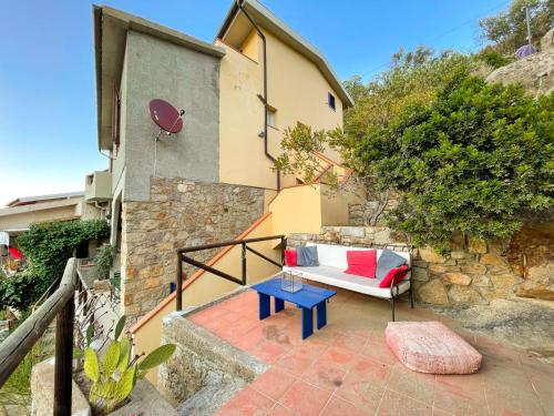 a patio with a couch and a blue table at Casa Caretta con terrazza panoramica in Isola del Giglio