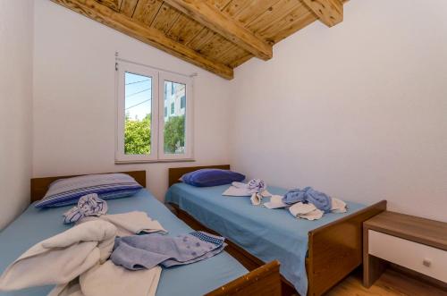 two twin beds in a room with a window at Kuća Neven in Stomorska