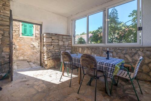 a table and chairs in a room with windows at Kuća Neven in Stomorska
